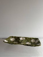 Front view of ceramic tray showing green background with white daisy flowers.