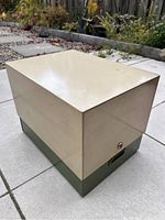 Exterior angled view of vintage filing box showing beige top and green base.