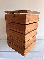 Wooden wall storage unit with open top drawer showing dovetail joins and natural wood grain.