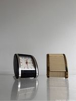 Side view of two Westclox travel clocks, highlighting body textures and profile.