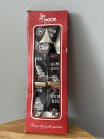 Front view of suspenders in original red box showing the full length and design with Santa faces and 'HUM BUG' text.
