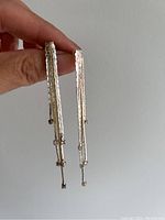 Close-up front view of the pair of silver disco dangling earrings showing hammered texture and decorative elements.