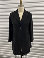 Front view of the women's black one button blazer on a dress form, showing the full length and button detail.