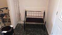Photo showing brass coat rack with curved hooks and metal bench with brass finials