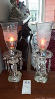 Pair of leaded crystal lamps with removable fluted glass shades on wood table, glowing with light