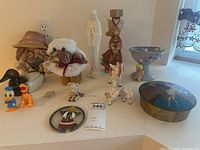 Various figurines including ducks, elephants, angels, doll, horses, and decorative dish arranged on a counter