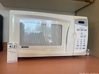 Front view of white Kenmore microwave showing size and door with transparent window and mesh