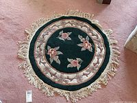 Full view of the round floor rug showing floral pattern, border, and fringe edges.