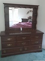 Full view of wood dresser with attached mirror showing overall design and size.