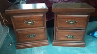 Front view of two matching wood nightstands showing the brass handles and drawer fronts