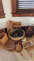 Full lot of wicker and rattan baskets arranged on floor under window light.