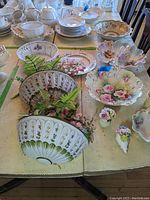 Top view showing Italian ceramic wall planters with floral decorations, multiple decorative bowls, and Little Orphan Annie cup with chips.