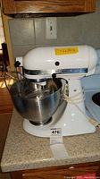 Full view of white KitchenAid Classic K45SS stand mixer on countertop with stainless steel mixing bowl attached.