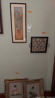 Wall view showing tall Asian print (left) and square floral tray (right), plus two framed needlepoint portraits on floor
