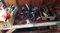 Photo showing various power tools including Skilsaw circular saw, sanders, clamps on wooden shelf with lots of dust and rust spots