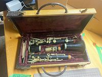 Full clarinet in open carrying case with a small bundle of reeds inside the case.