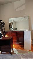 Full view of the vintage wooden dresser with attached large mirror and new white IKEA shelf beside it, plus the nightstand in front.