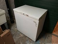 White Woods-Custom brand chest freezer positioned in basement, rectangular shape with control panel switches on top front edge.