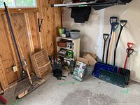 Wide angle photo showing rakes, broom, stacked empty pots, snow shovels on the floor, and bags of soil.
