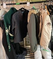 Overview of four garments hung on metal rack in basement