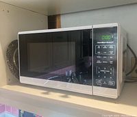 Front and side views of stainless steel Hamilton Beach microwave with digital control panel.