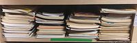 Wide shelf view showing numerous stacked sheet music books horizontally arranged in piles.