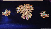 Front view of Sherman vintage brooch and earrings on dark blue velvet background showing sparkling aurora borealis rhinestones.