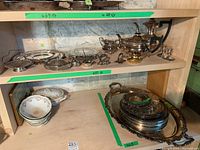Shelf with silver plate trays, tea and coffee pots, sugar and cream containers, and ceramic bowls
