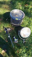 Lot items arranged on grass: vintage fire truck light, fire hose nozzle, speaker on pole, and black metal boiler pot with lid.