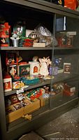 Wide view of shelf display with multiple boxed and loose vintage Christmas ornaments, including Hallmark and Disney brand items as well as glass balls.
