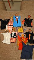 Overview photo showing 10 vintage hand puppets arranged on carpet. Puppets have colorful fabrics and paper mache heads depicting various characters including clowns and monsters.