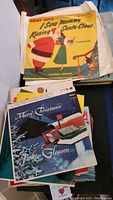 View of the record collection showing the Jimmy Boyd 'I Saw Mommy Kissing Santa Claus' 45 RPM and Jackie Gleason Merry Christmas LP on top.