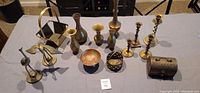 Overview of all brass items laid out on table with lot number card.