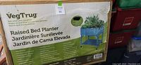 Front of box showing product name VegTrug Raised Bed Planter with product image and multilingual description.