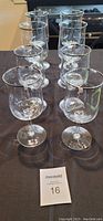 Overall view of eight clear crystal stemware glasses with platinum rims, four larger water goblets and four smaller wine glasses.