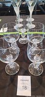 Six clear crystal wine glasses with rounded bowls and faceted spherical stems, shown on a dark surface.