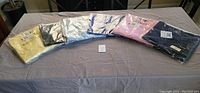 Six plastic-wrapped Talbots Charming Cardigan Sweaters arranged side by side on a table.