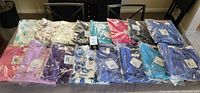 Overall view of eleven packaged Talbots Charming Cardigan Sweaters in various solids and prints laid out on table