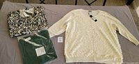 Three Talbots women's cardigans, size 2X, laid flat. One cream textured with floral pattern, one black and white patterned, one green in packaging.