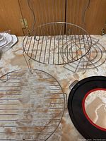 Photo showing several wire racks in different shapes and sizes on a marble countertop.