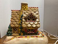 Front angle showing detailed candy accents, chimney, and light bulbs on the house front.