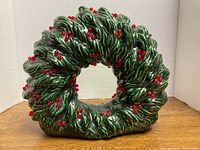 Front view of ceramic tabletop wreath showing green pine boughs and red berries