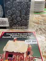 Photo showing a clear plastic chocolate mold sheet with various snowflake shapes and part of the gingerbread house bake set box, lot number visible.