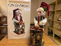 Image showing the Jacqueline Kent Collection Christmas Elf figurine 'Mender Master' next to its original box, highlighting the detailed craftsmanship and festive design.