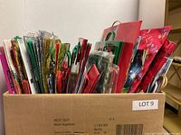 Box containing multiple Christmas gift bags, various designs and colors, showing front view of bags and handle types.