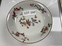 Top view of one Limoges plate showing colorful floral pattern and gold rim with LOT 260 sticker