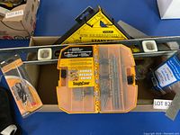 Overview of Stanley roofing square, Stanley metal level, and ToughCase with drill bits and screws on blue surface