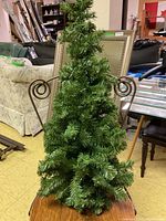 Full view of one small artificial Christmas tree with metal wire frame for wall mounting, showing overall shape and branch density.