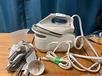 Rowenta steam iron with base unit and accessories on table showing all included items in lot