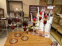 Set of three painted glass candle holders in front of original box, showing decorative paint and sizes.